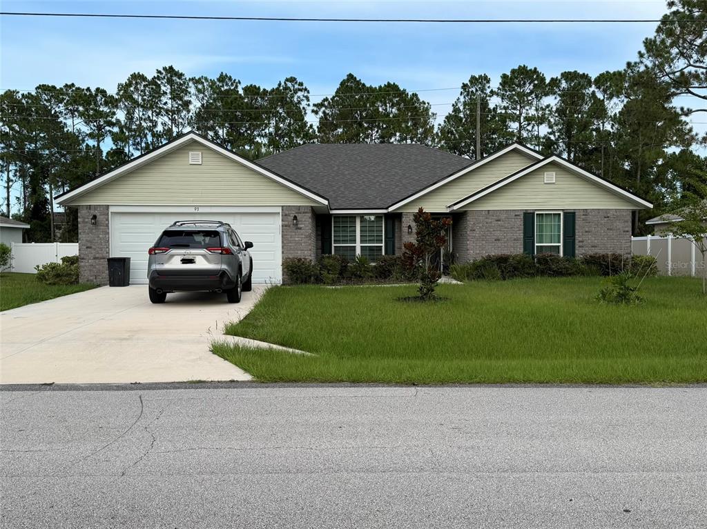 A single-story house with a brick and light green siding exterior, a two-car garage, and a driveway — 93 ROYAL OAK DRIVE, PALM COAST, FL