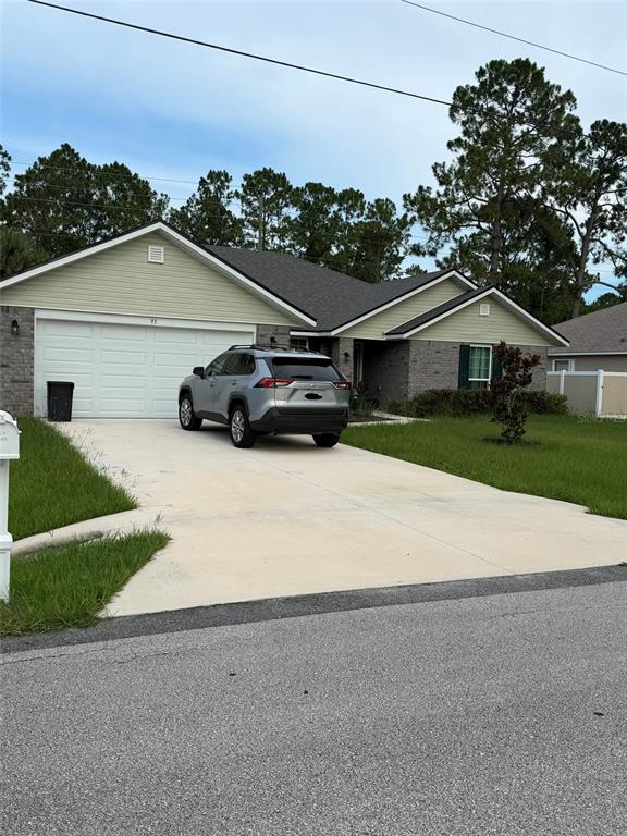 A single-story house with a brick and light green siding exterior features a concrete driveway — 93 ROYAL OAK DRIVE, PALM COAST, FL