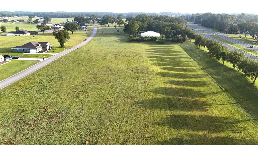 An aerial view shows a large, grassy vacant lot bordered by a road and trees — XX NW 17TH CIRCLE, OCALA, FL