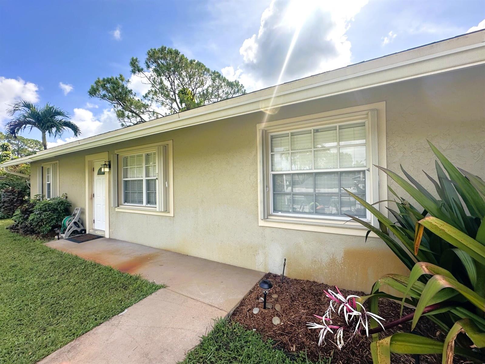 A single-story house exterior features a beige stucco facade, white trim, and a concrete walkway — 5586 3rd Road, Lake Worth FL 33467, LAKE WORTH, FL