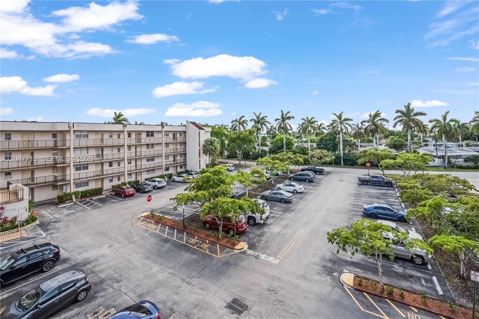 An elevated view of an apartment building exterior with a large parking lot and palm trees — 2551 Aragon Blvd # 411, Sunrise FL 33322, SUNRISE, FL