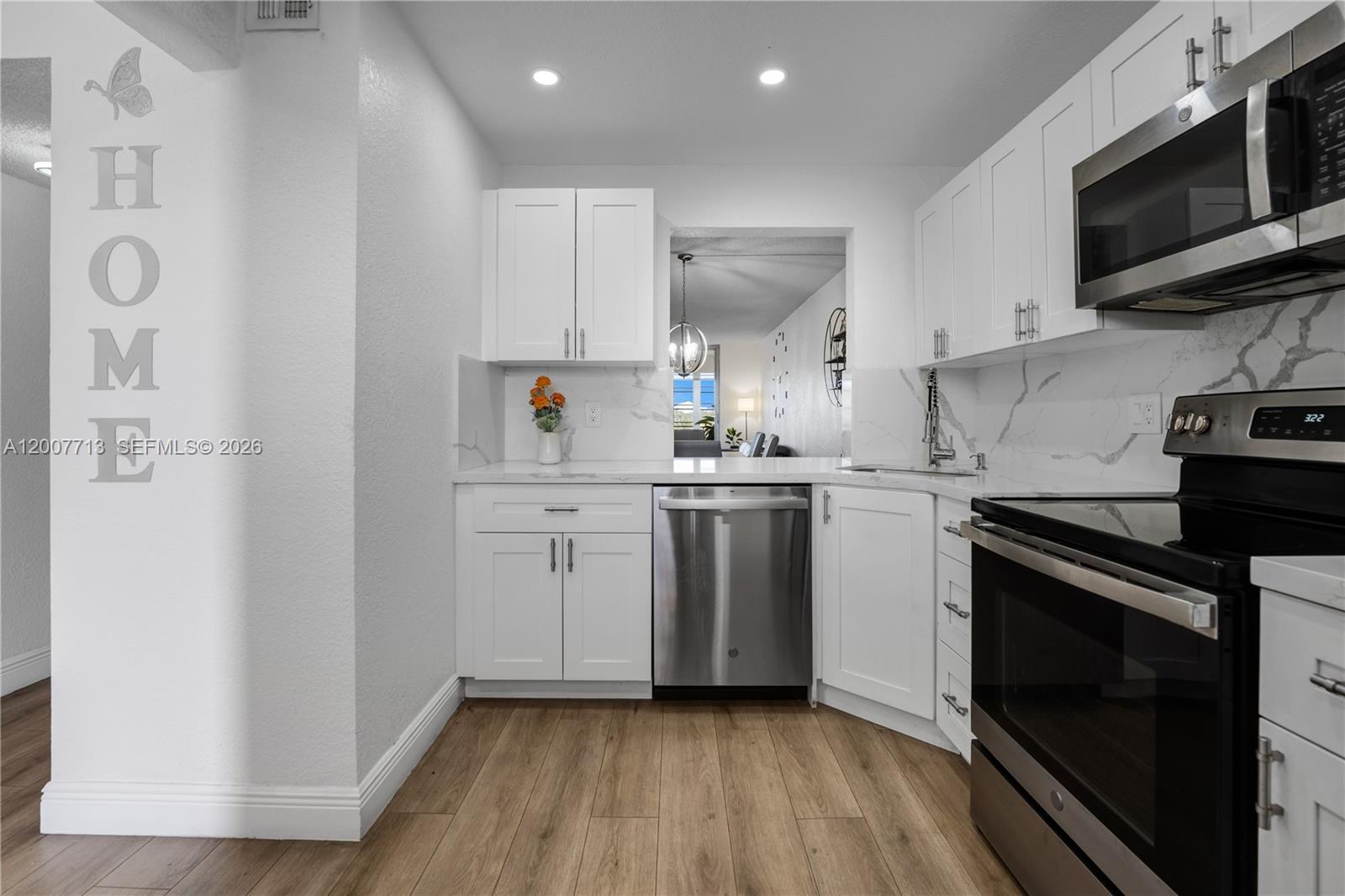 A modern kitchen features white cabinets, stainless steel appliances, and marble-look countertops — 2551 Aragon Blvd # 411, Sunrise FL 33322, SUNRISE, FL