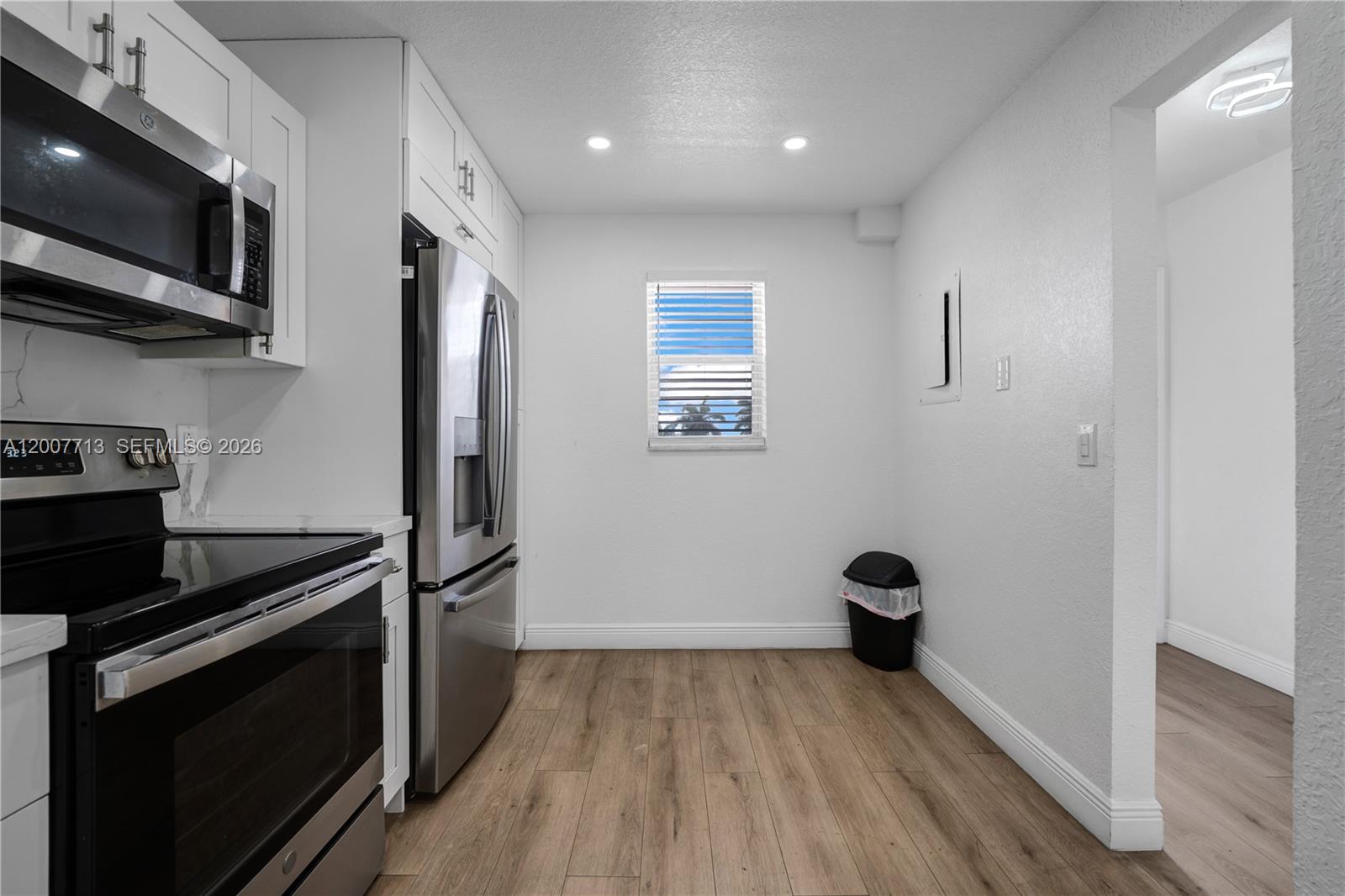 A kitchen features white cabinets, stainless steel appliances, and light wood-look flooring — 2551 Aragon Blvd # 411, Sunrise FL 33322, SUNRISE, FL