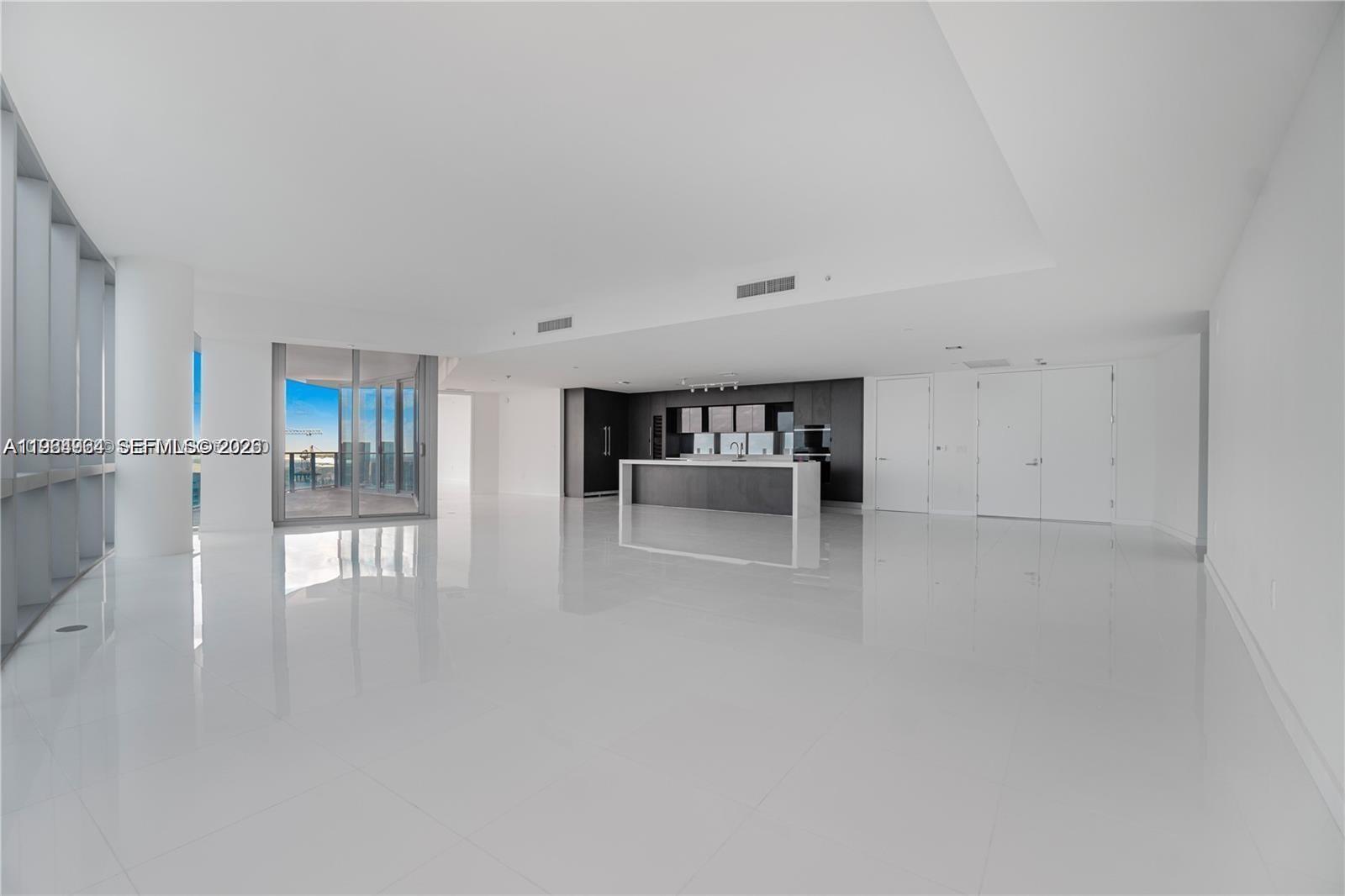 A spacious, minimalist open-concept living area features white tile floors and a modern kitchen — 851 NE 1st Ave # 4911, Miami FL 33132, MIAMI, FL