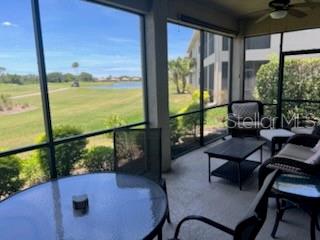 A screened-in porch features a glass table, patio furniture, and views of a golf course — 8406 GRAND ESTUARY TRAIL UNIT 104, BRADENTON, FL