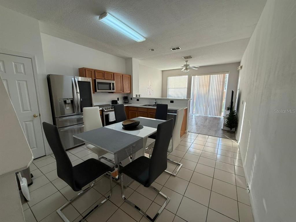 A kitchen with stainless steel appliances and a dining area with tile flooring — 5210 PARADISE CAY CIRCLE, KISSIMMEE, FL