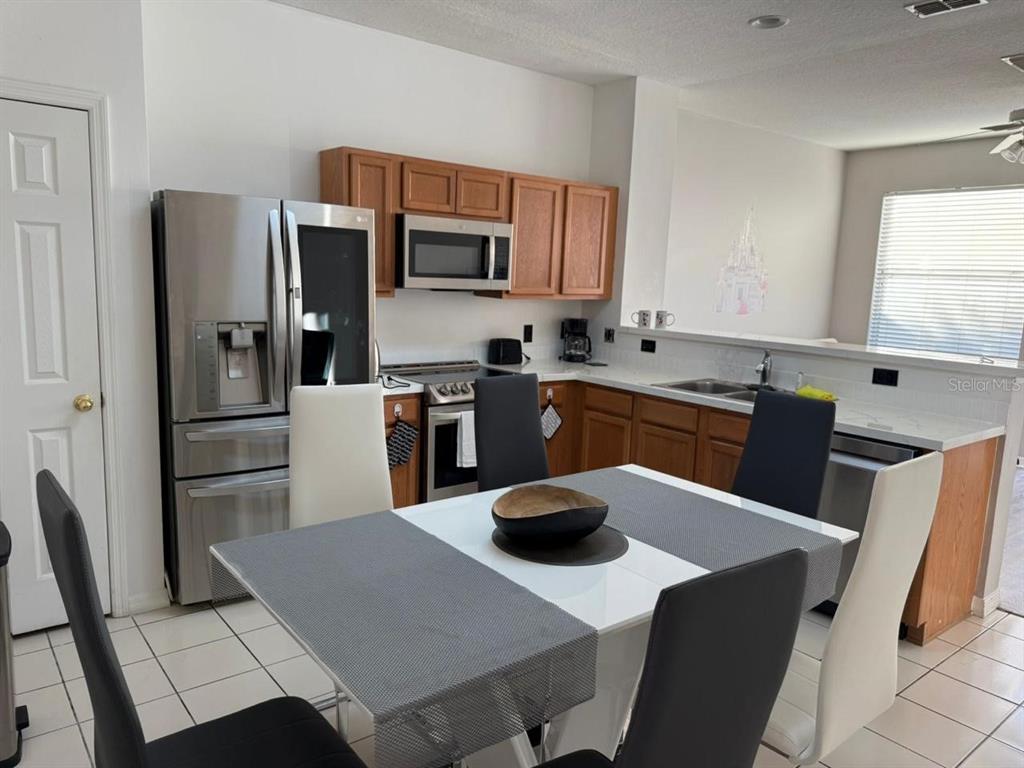 A kitchen with wood cabinets, stainless steel appliances, and a dining table with six chairs — 5210 PARADISE CAY CIRCLE, KISSIMMEE, FL