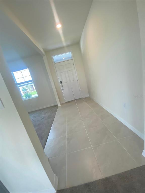 An entryway with light-colored tile flooring leads to a white front door — 701 SILVER PALM DRIVE, HAINES CITY, FL