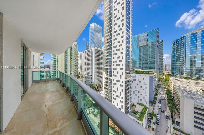 A balcony with a glass railing overlooks a dense urban skyline of modern high-rise buildings — 1331 Brickell Bay Dr # 1602, Miami FL 33131, MIAMI, FL