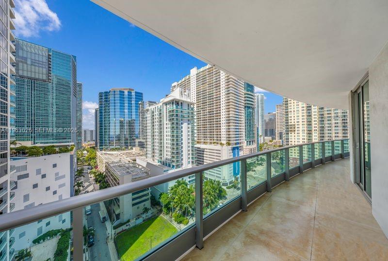 A high-rise balcony overlooks a dense urban cityscape with modern glass skyscrapers and palm trees — 1331 Brickell Bay Dr # 1602, Miami FL 33131, MIAMI, FL