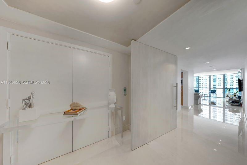 A modern entryway features a large white door, glossy floors, and a glass console table — 1331 Brickell Bay Dr # 1602, Miami FL 33131, MIAMI, FL