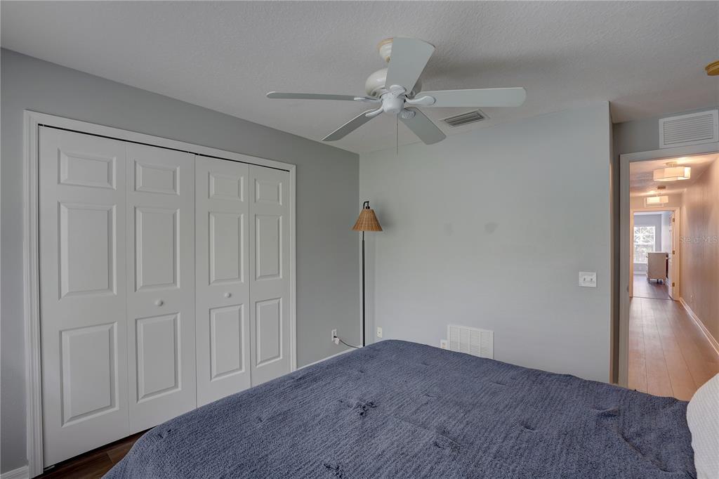 A bedroom features a blue bed, a ceiling fan, a closet, and a doorway — 9516 CHARLESBERG DRIVE, TAMPA, FL
