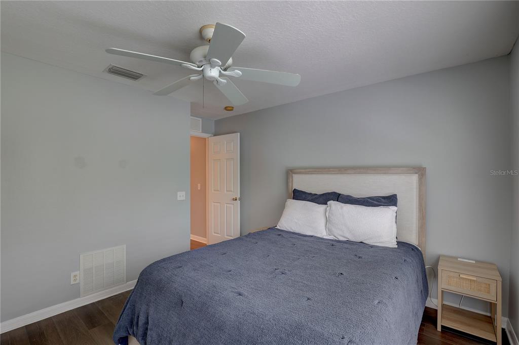 A bedroom features a bed with a blue quilt, a ceiling fan, and gray walls — 9516 CHARLESBERG DRIVE, TAMPA, FL