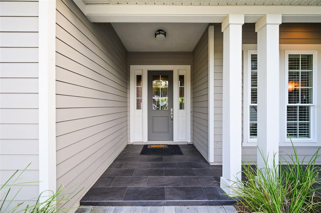 A covered front porch features gray horizontal siding, a dark tiled floor, and a gray door — 4074 NW 63RD STREET, GAINESVILLE, FL