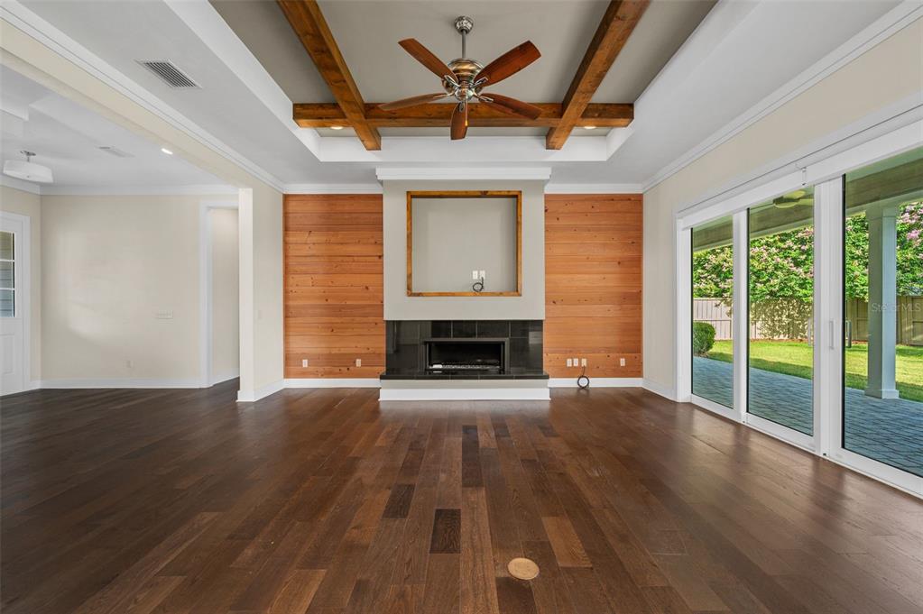 A living room features a coffered ceiling with wood beams, a fireplace, and wood-paneled walls — 4074 NW 63RD STREET, GAINESVILLE, FL