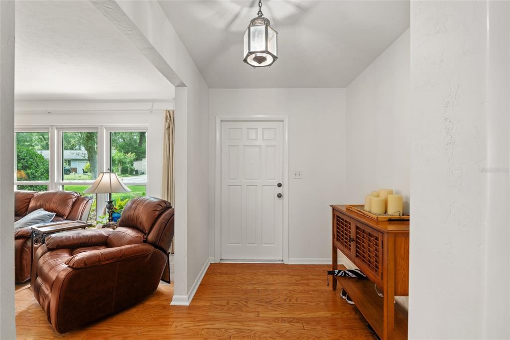 An entryway with hardwood floors, a white door, and a wooden console table — 3859 NW 32ND PL, GAINESVILLE, FL
