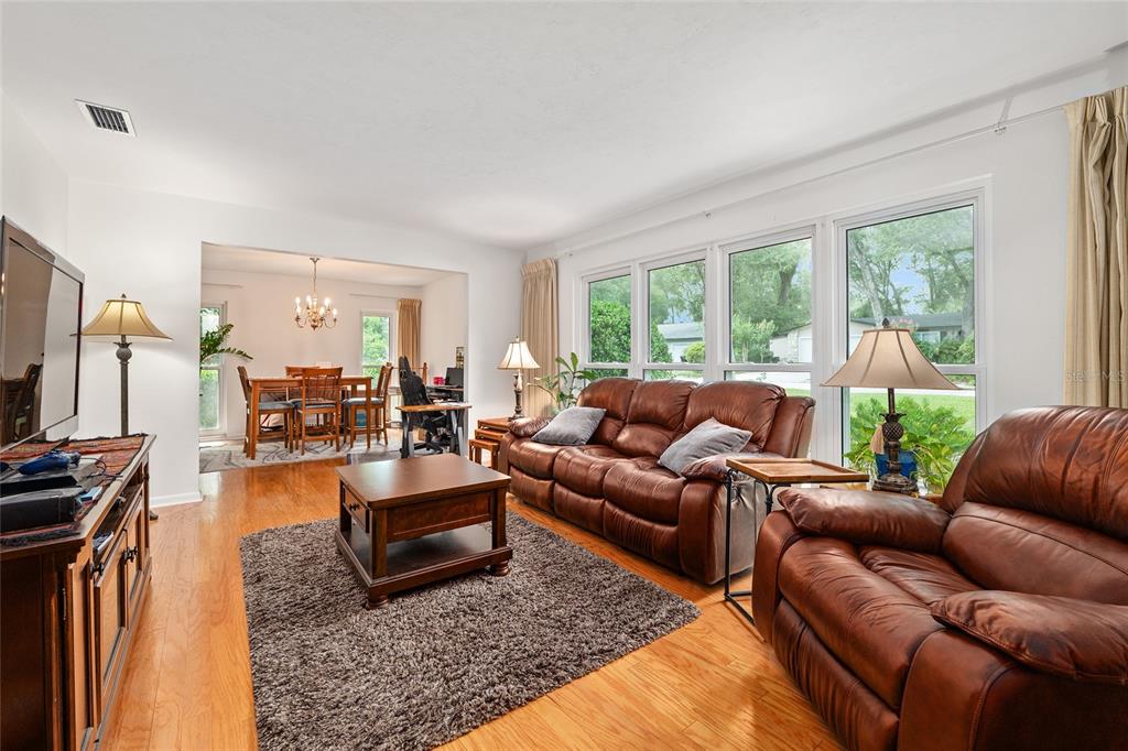 A living room with hardwood floors, a brown leather sofa set, and an adjacent dining area — 3859 NW 32ND PL, GAINESVILLE, FL