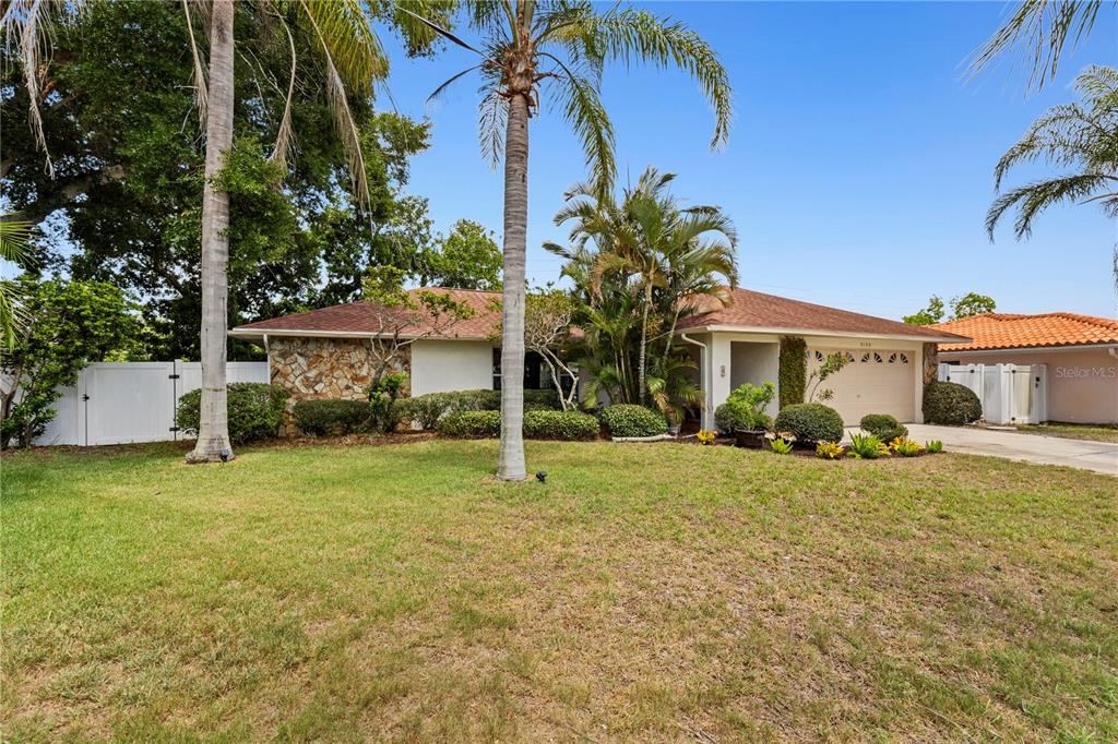 A single-story house with a stone facade, a two-car garage, and palm trees in front — 3153 CARLOS DRIVE, DUNEDIN, FL