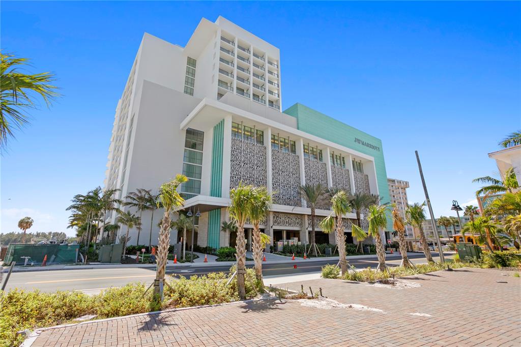 A modern JW Marriott hotel building stands beside a street with palm trees and landscaping — 691 S GULFVIEW BOULEVARD UNIT 1412, CLEARWATER BEACH, FL