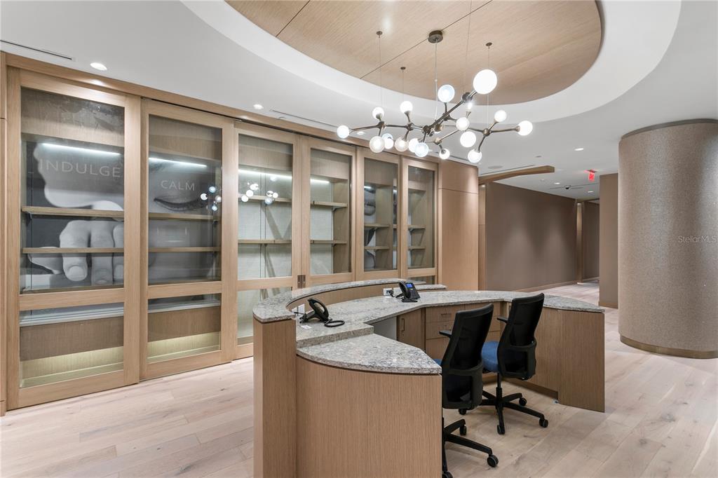A curved reception desk sits in a modern office lobby with light wood cabinetry and flooring — 691 S GULFVIEW BOULEVARD UNIT 1412, CLEARWATER BEACH, FL