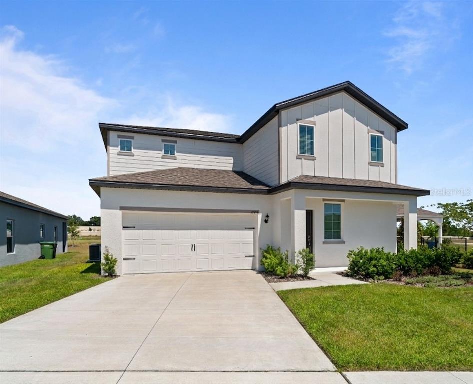 A two-story house with a white stucco facade, a two-car garage, and a concrete driveway — 1774 WHITE ELEPHANT LOOP, WINTER HAVEN, FL