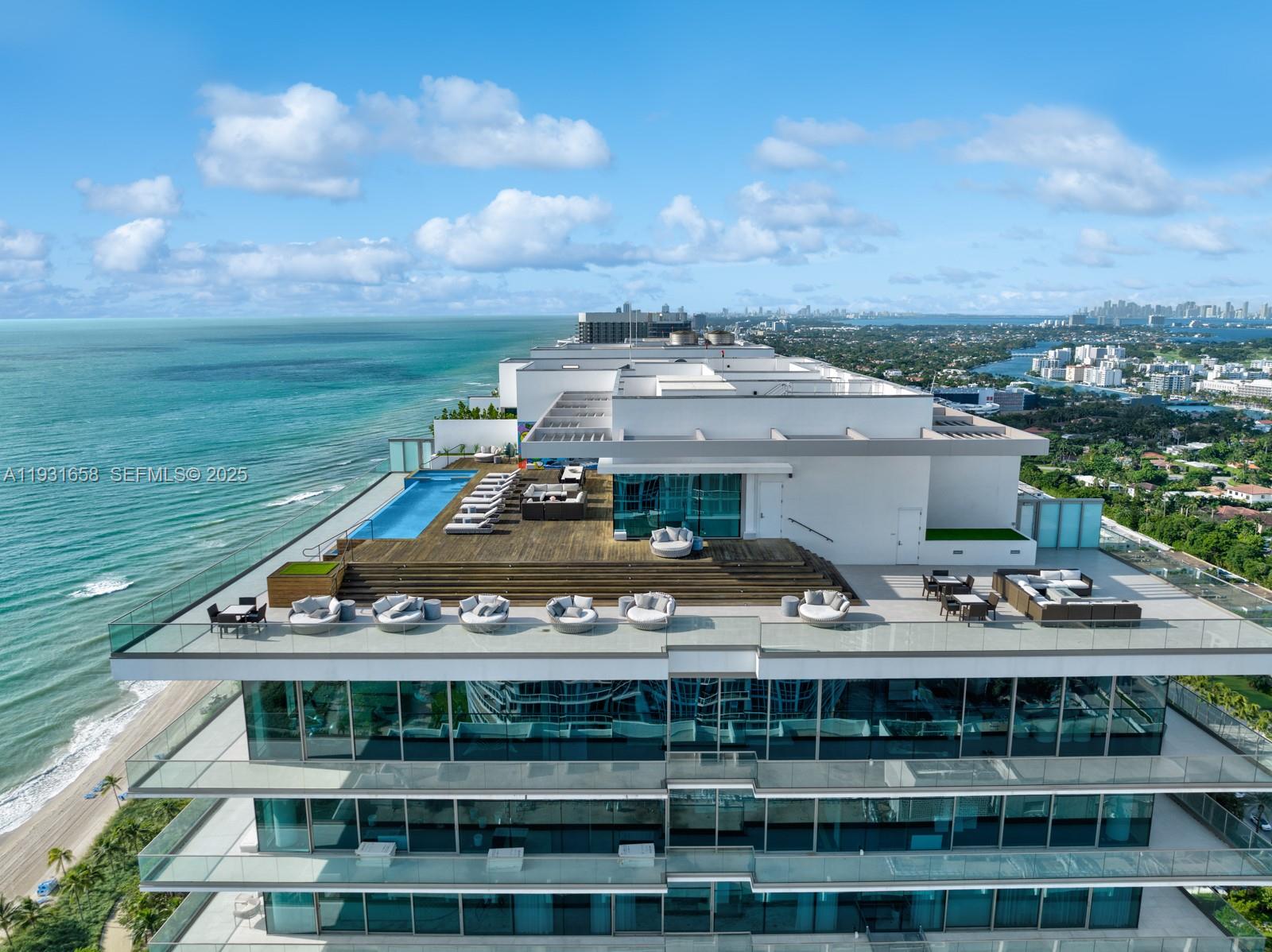 An aerial view of a modern building rooftop featuring a swimming pool and lounge area — 10203 Collins Ave # 2801, Bal Harbour FL 33154, BAL HARBOUR, FL