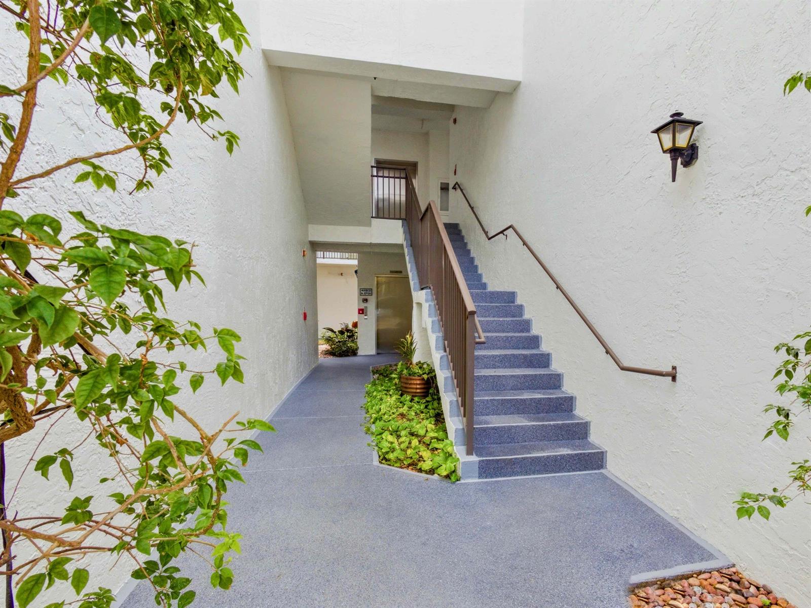 An outdoor staircase with blue steps leads to an upper level next to a walkway — 5265 Brisata Circle # P, Boynton Beach FL 33437, BOYNTON BEACH, FL