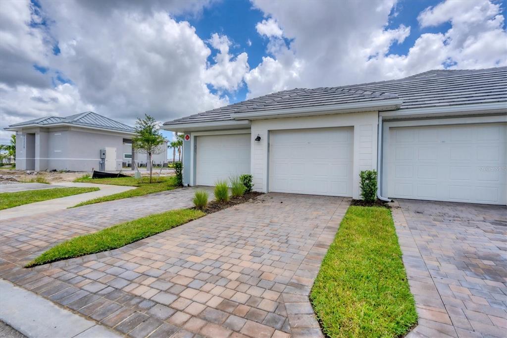 A view of the exterior of a suburban home with paver driveways and garage doors — 14224 HEIRTAGE LANDING BOULEVARD UNIT 921, PUNTA GORDA, FL