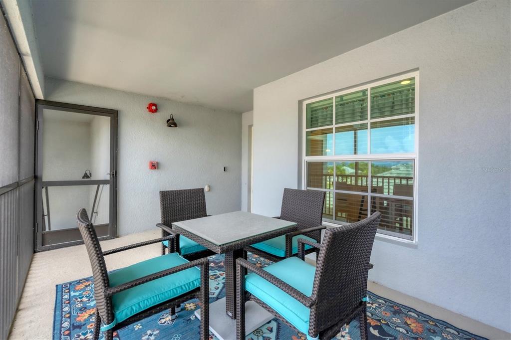 A covered balcony features a four-person dining set on a patterned rug — 14224 HEIRTAGE LANDING BOULEVARD UNIT 921, PUNTA GORDA, FL