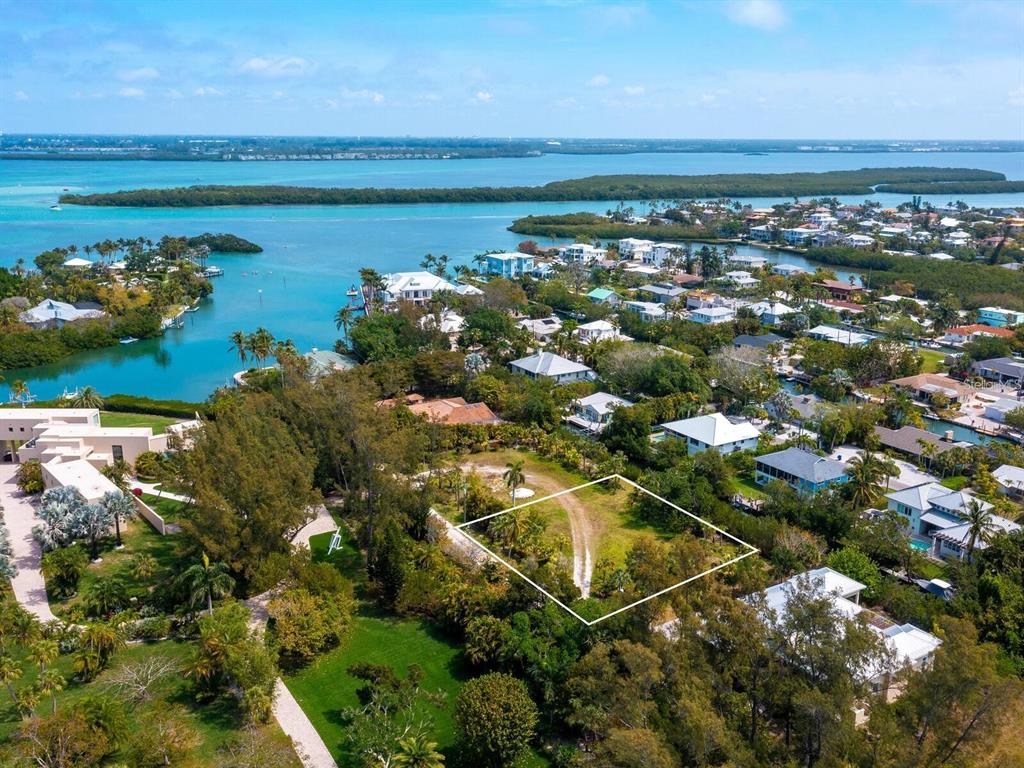 An aerial view shows a vacant, rectangular lot outlined in white amidst a coastal neighborhood — 6608 GULF OF MEXICO DRIVE, LONGBOAT KEY, FL