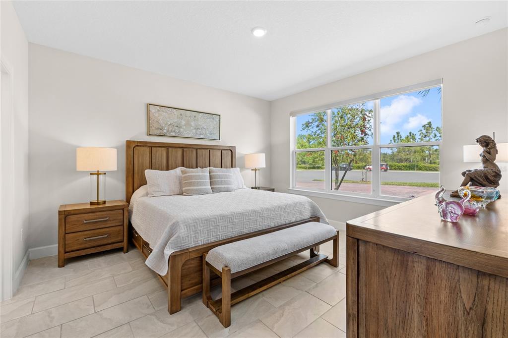 A bedroom features a wooden bed frame, a bench, two nightstands, and a large window — 1309 LOMBARDI COURT, KISSIMMEE, FL