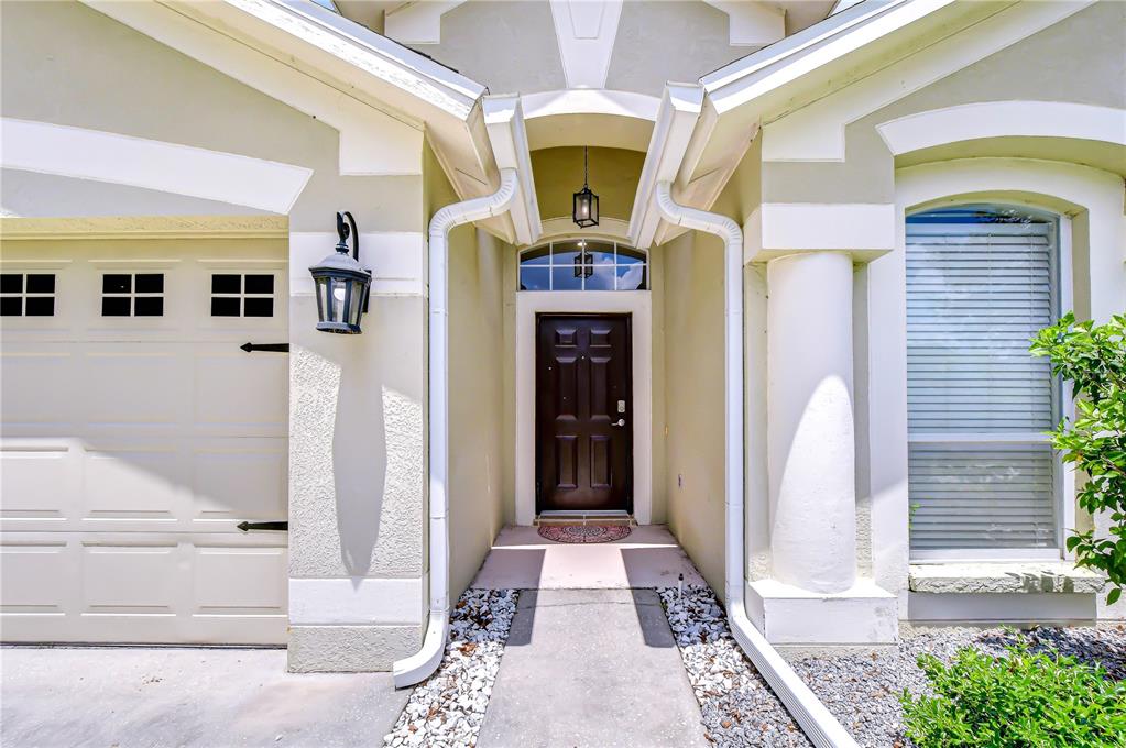 The exterior of a house features a dark front door, a garage, and a column — 19707 ELLENDALE DRIVE, LAND O LAKES, FL