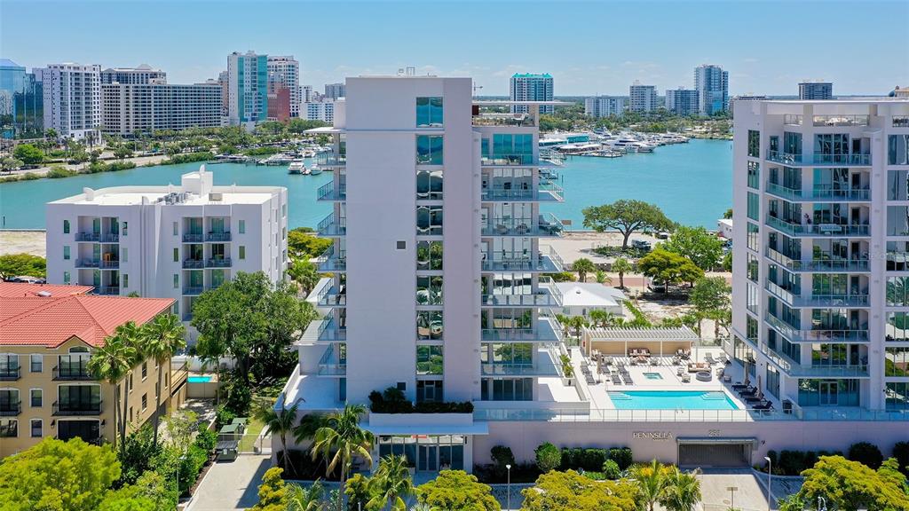 An aerial view shows a multi-story residential building with a pool and waterfront marina — 253 GOLDEN GATE POINT UNIT 401, SARASOTA, FL