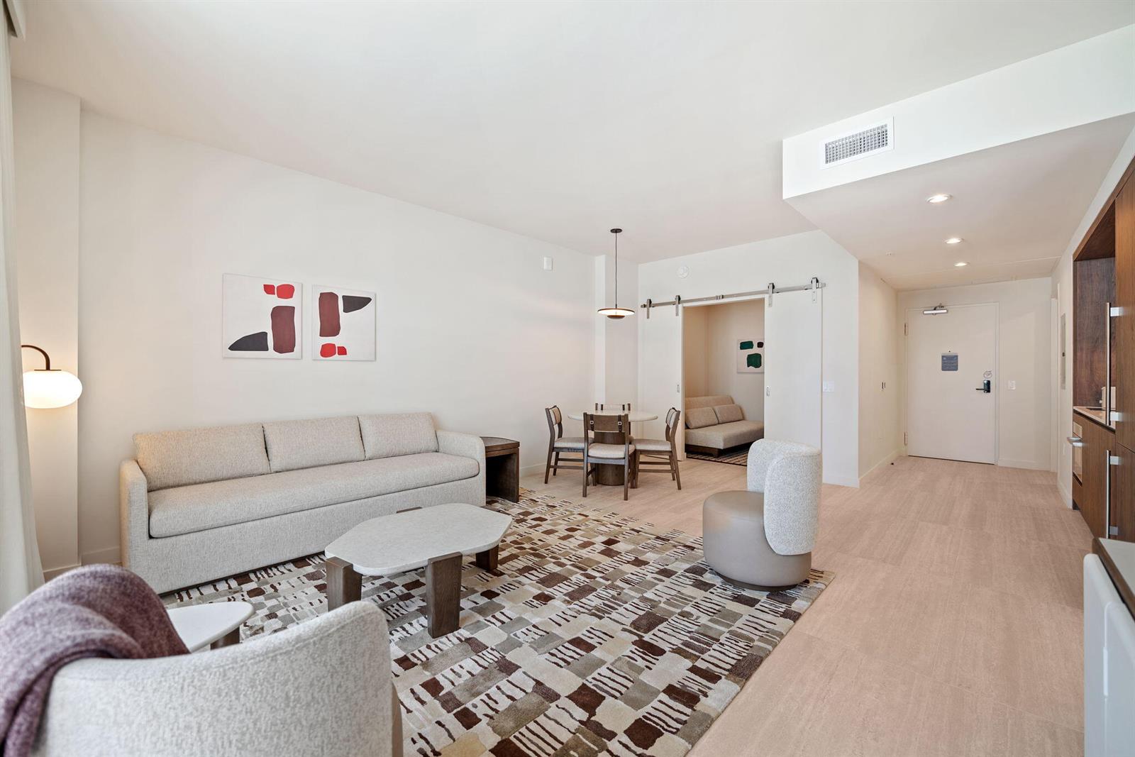 A modern living room features a sofa, dining area, patterned rug, and sliding barn doors — 1611 SW 2nd Avenue # 702, Miami FL 33129, MIAMI, FL