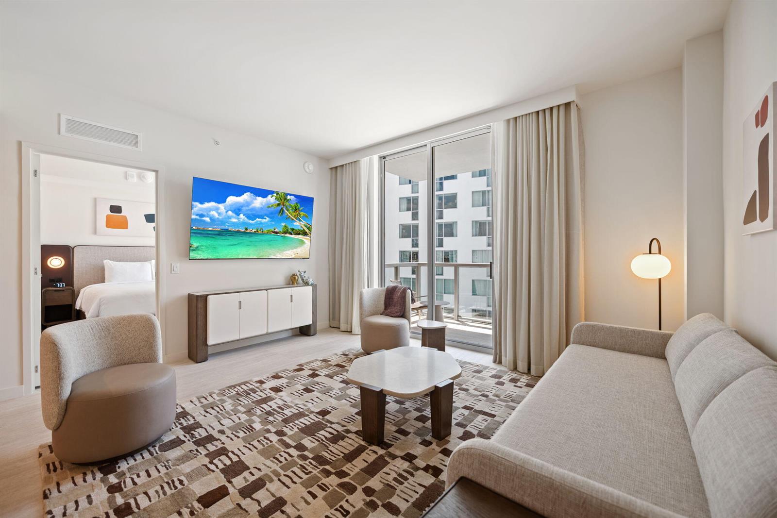 A modern living room features a sofa, armchairs, a patterned rug, and a wall-mounted television — 1611 SW 2nd Avenue # 702, Miami FL 33129, MIAMI, FL