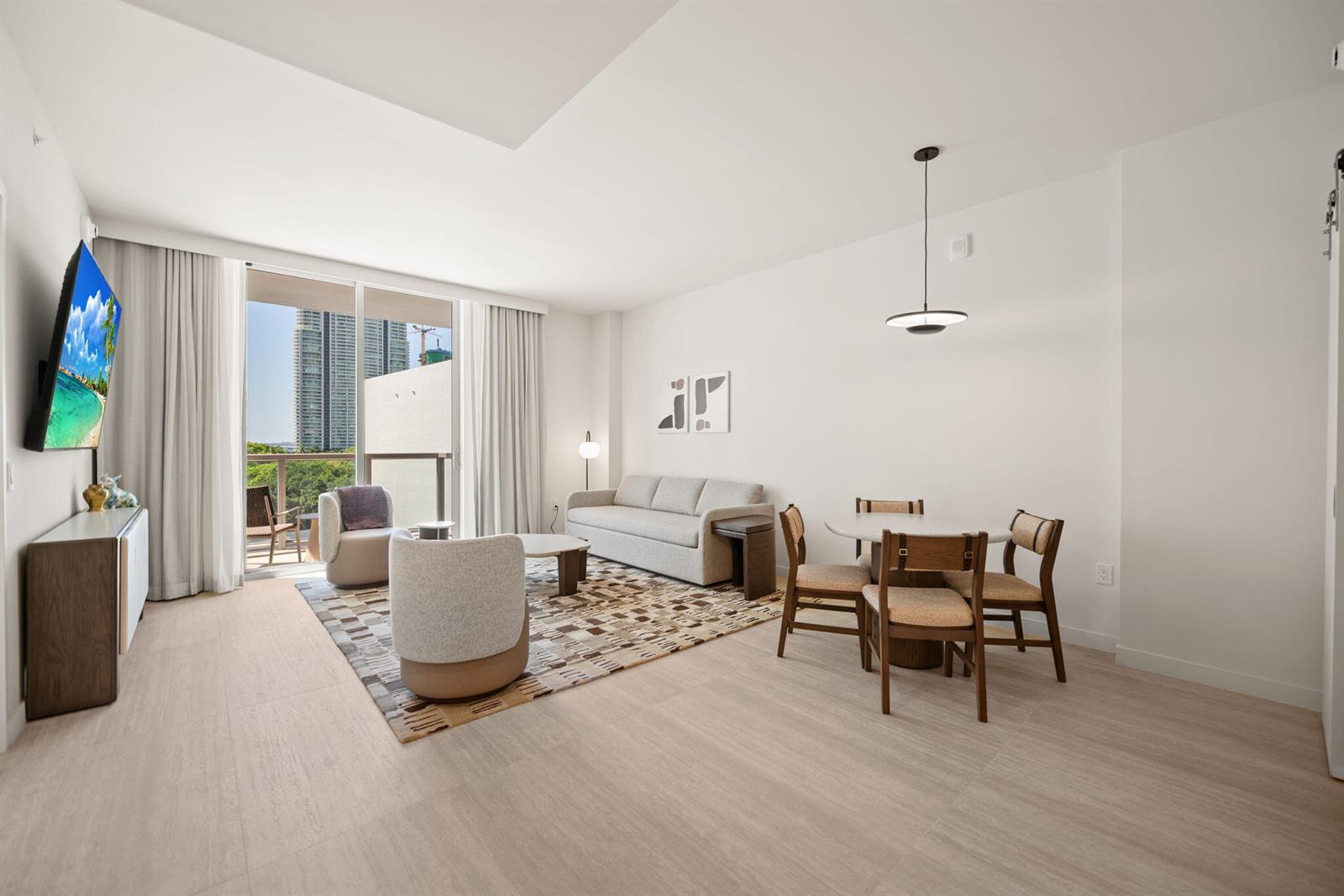 A bright living and dining area features a sofa, armchairs, and a balcony with views — 1611 SW 2nd Avenue # 702, Miami FL 33129, MIAMI, FL