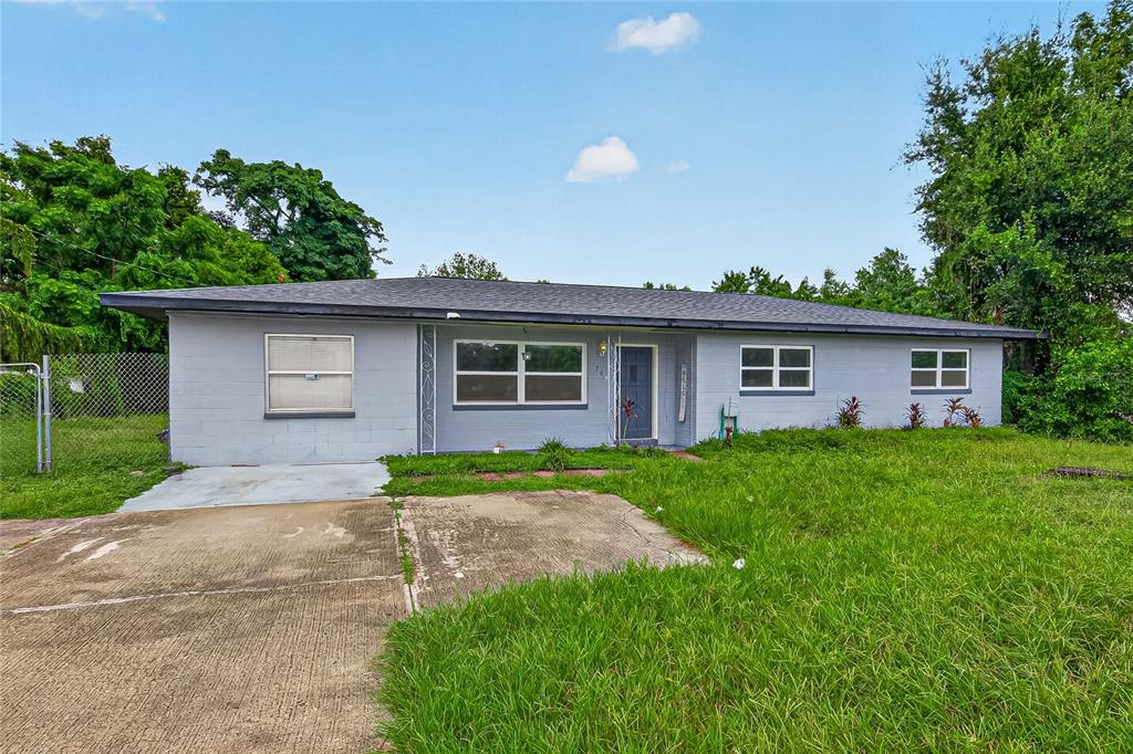 A single-story gray house with a concrete driveway and a chain-link fence on the left — 708 N PARSONS AVENUE, BRANDON, FL