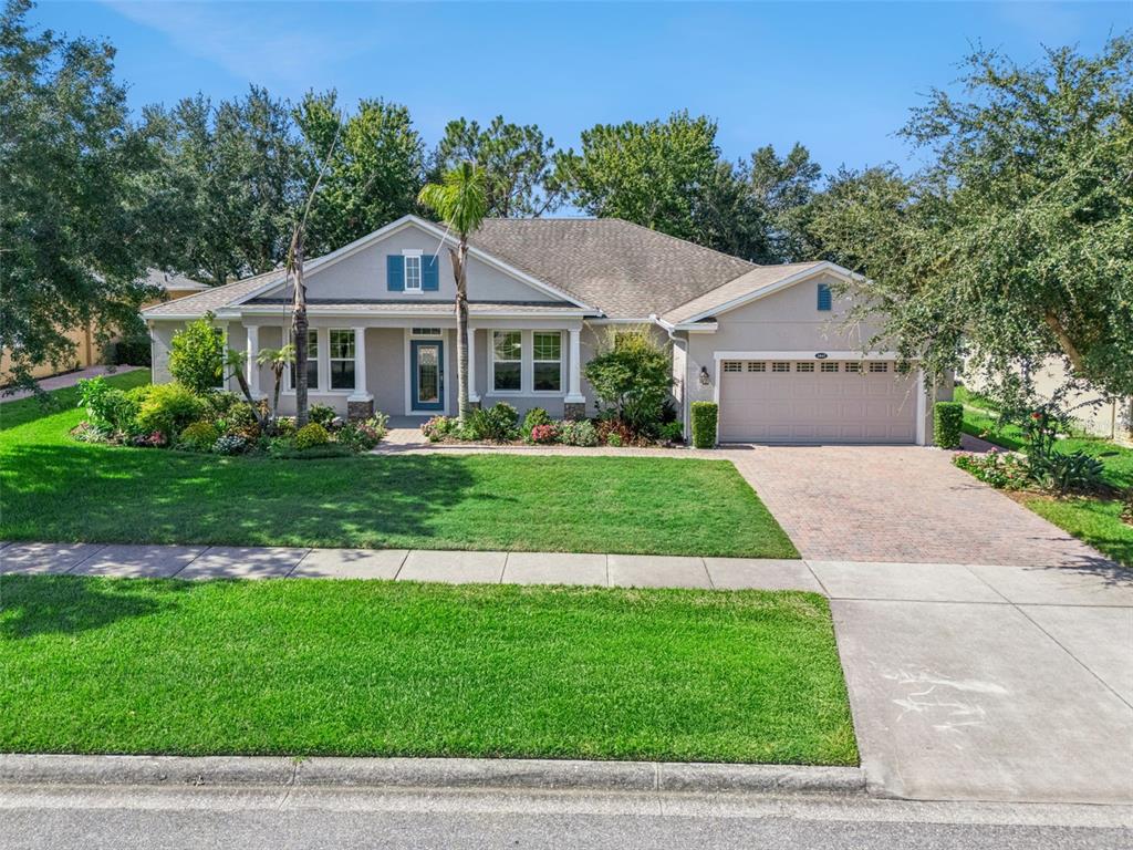 A single-story suburban house with a beige exterior, a two-car garage, and a landscaped yard — 1041 HARMONY LANE, CLERMONT, FL