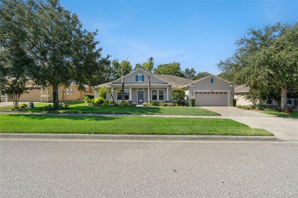 A single-story house with a beige exterior, a two-car garage, and a manicured front lawn — 1041 HARMONY LANE, CLERMONT, FL