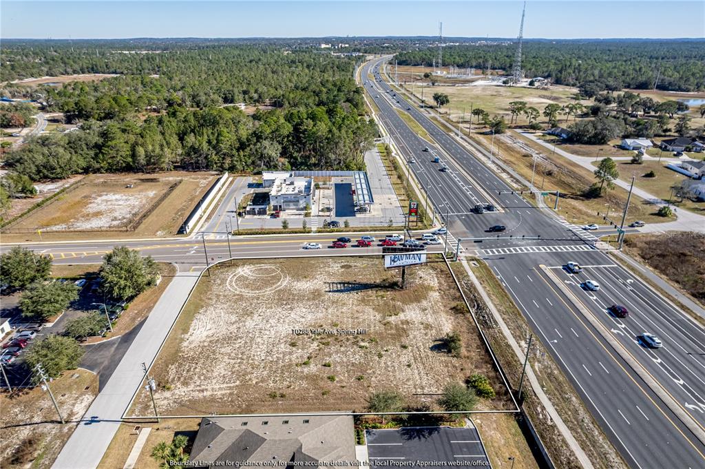 An aerial view shows a vacant, rectangular lot situated next to a highway and commercial development — 10288 Lot 8 YALE AVENUE, WEEKI WACHEE, FL