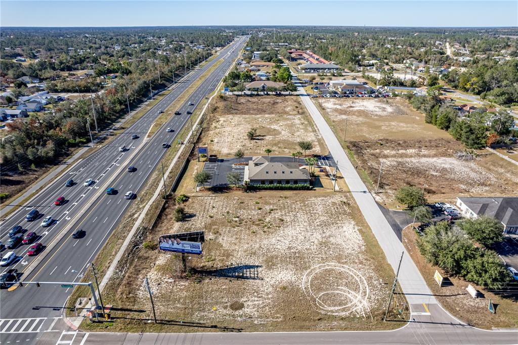 An aerial view shows a commercial building situated on a large, undeveloped lot near a highway — 10288 Lot 8 YALE AVENUE, WEEKI WACHEE, FL