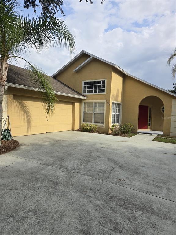 A tan, two-story house with a two-car garage, a concrete driveway, and a red door — 3127 VALLEY VISTA CIRCLE, LAKELAND, FL