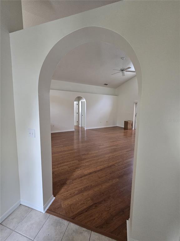 An arched doorway leads into a spacious living area with wood-look flooring and vaulted ceilings — 3127 VALLEY VISTA CIRCLE, LAKELAND, FL