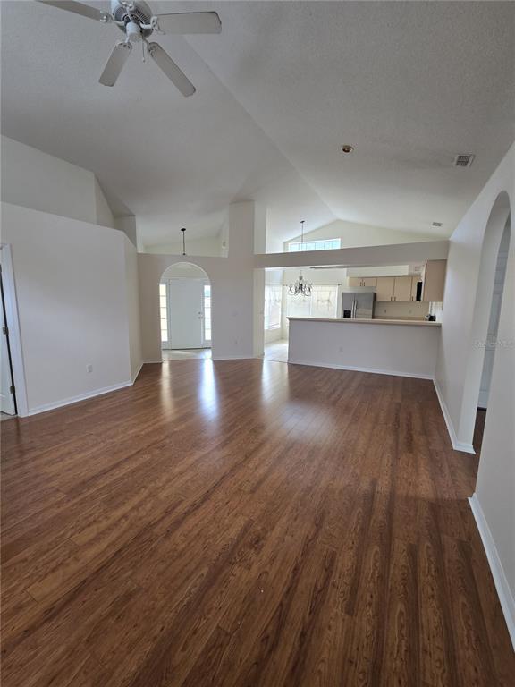 A living room with wood-look flooring, vaulted ceilings, and an open kitchen with a breakfast bar — 3127 VALLEY VISTA CIRCLE, LAKELAND, FL