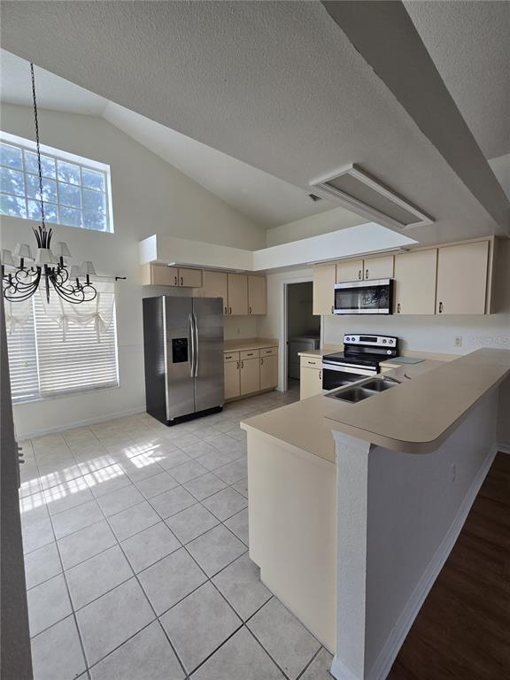 A kitchen with light-colored cabinets, stainless steel appliances, and tile flooring features a breakfast bar — 3127 VALLEY VISTA CIRCLE, LAKELAND, FL