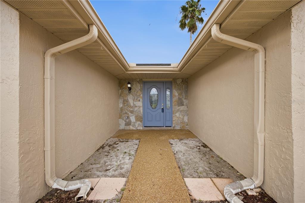 An exterior view of a home entrance with a light blue door and stone facade — 9840 SAN SEBASTIAN WAY, PORT RICHEY, FL