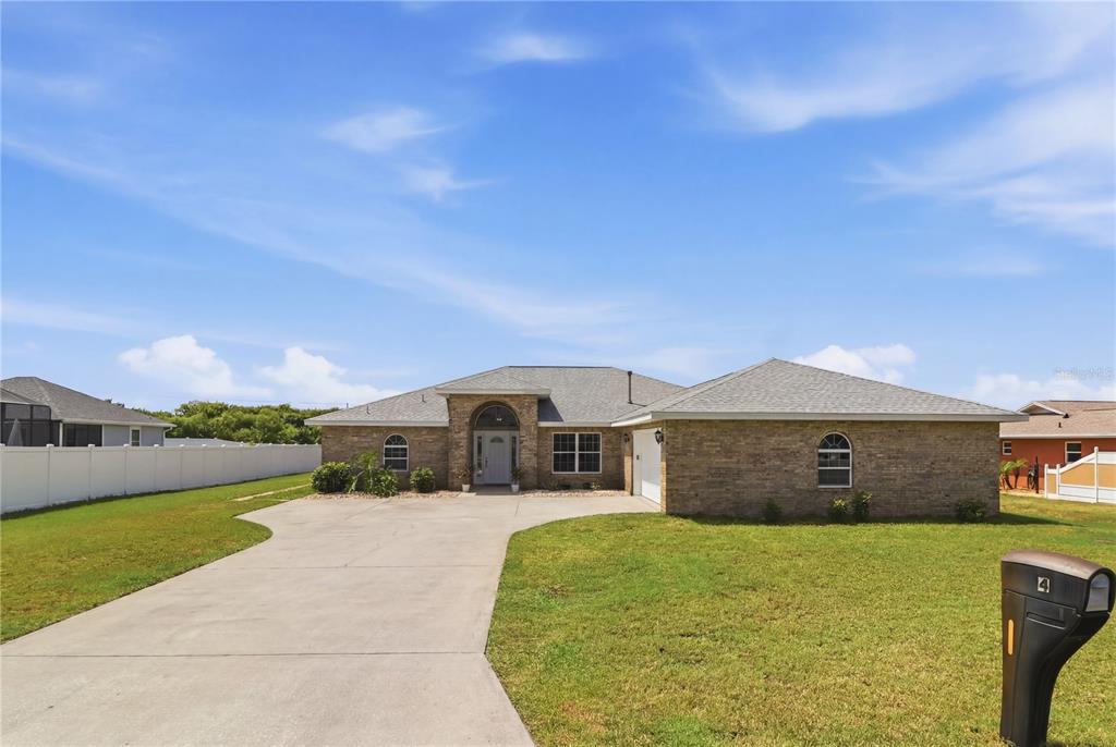 A single-story brick house with a concrete driveway and a white fence — 4 BEACHSIDE DR, PALM COAST, FL
