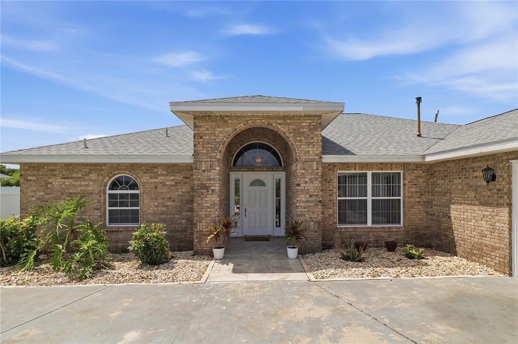 A single-story brick house features an arched entryway, a white front door, and a driveway — 4 BEACHSIDE DR, PALM COAST, FL