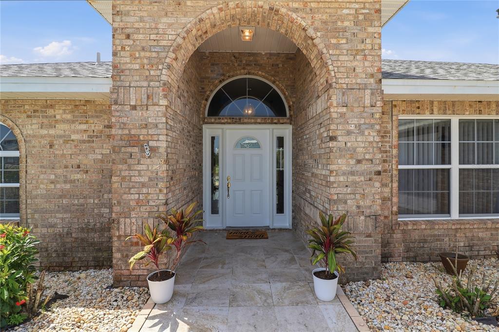 A brick home exterior features an arched entryway with a white front door and sidelights — 4 BEACHSIDE DR, PALM COAST, FL