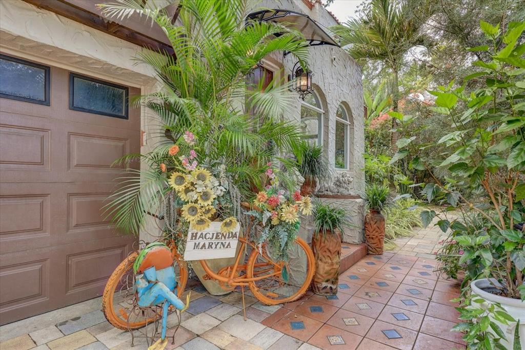 An orange decorative bicycle with flowers sits on a paved patio outside a house entrance — 325 49TH STREET N, ST PETERSBURG, FL